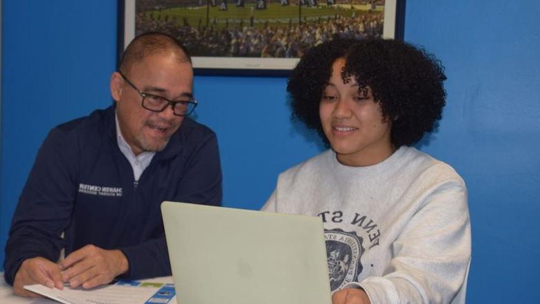 Student and staff member looking at laptop computer